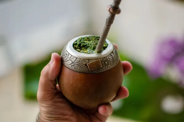 Mano sosteniendo un mate con yerba